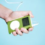 A hand holds a lime-green Apple iPod portable digital music player --- Image by © Royalty-Free/Corbis